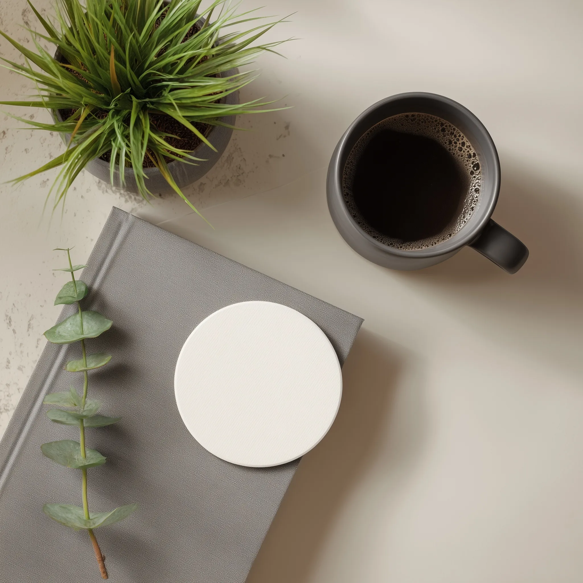 Top view of a blank round magnetic bookmark mockup next to a book, coffee cup, and houseplant in a modern setting.