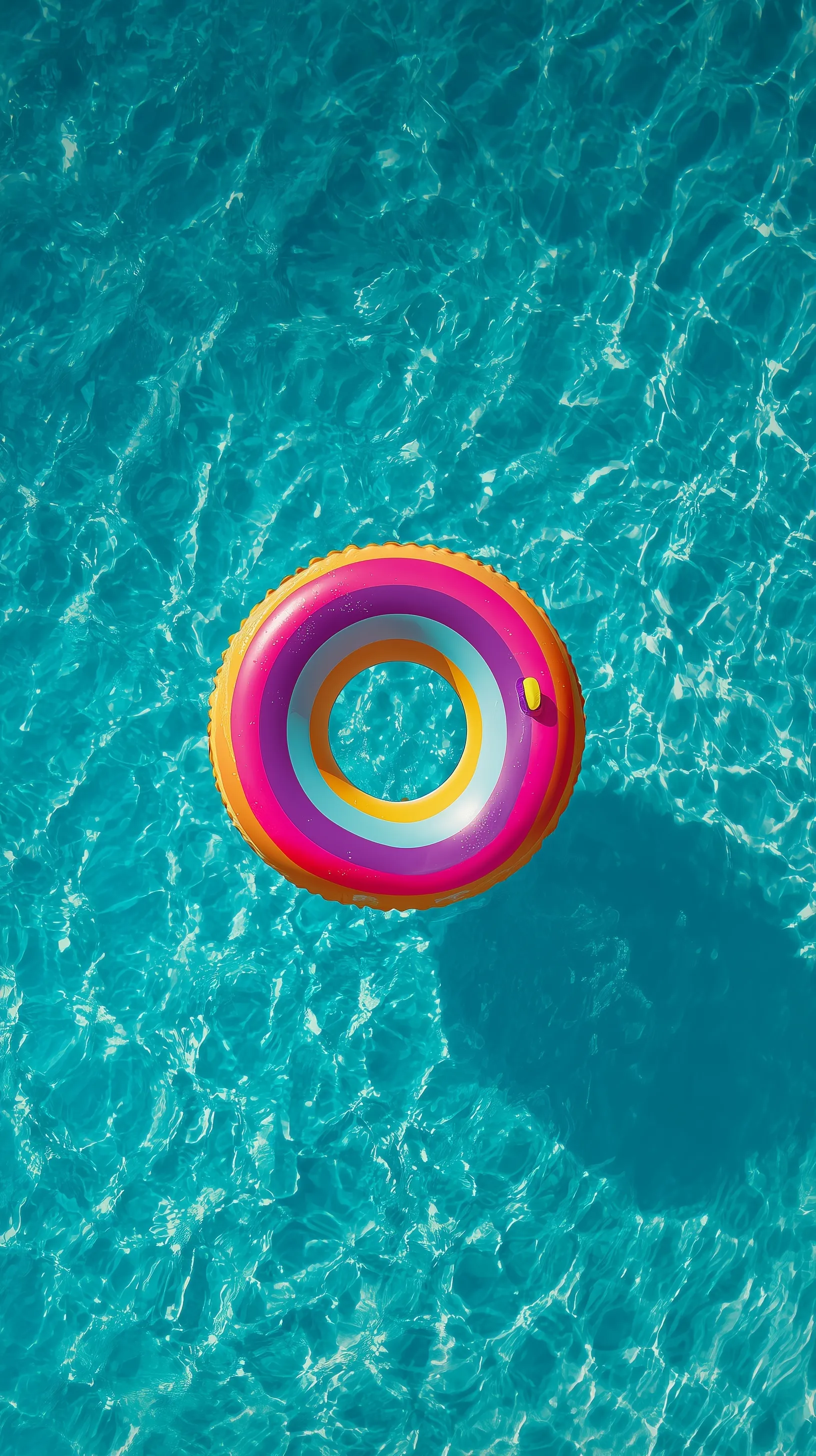 A colorful pool floatie drifting on bright turquoise ocean water under a soft pastel summer sky, drone view.