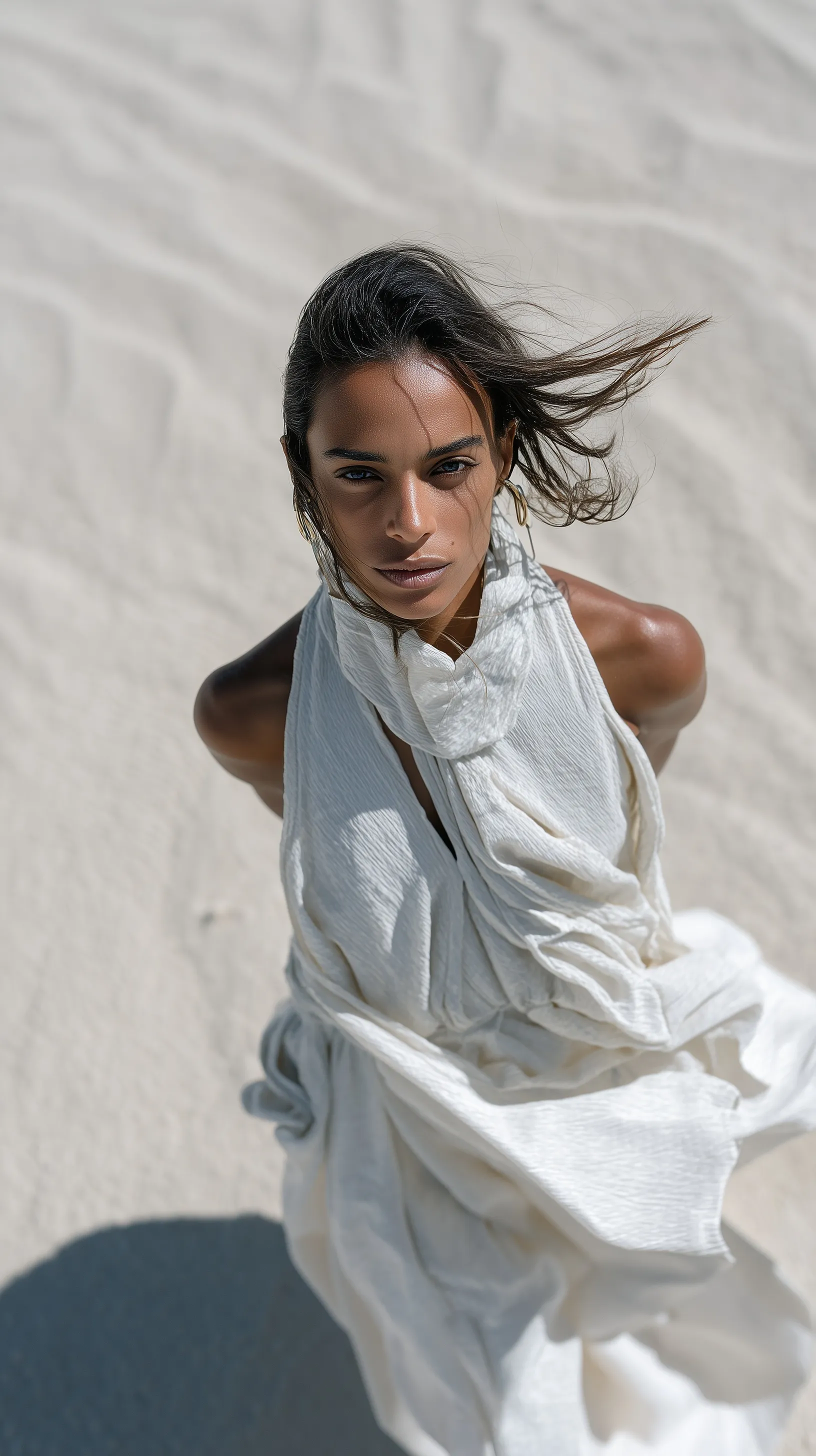 A Black woman in a flowing white silk dress standing in a vast desert, cinematic lighting, high-angle view.