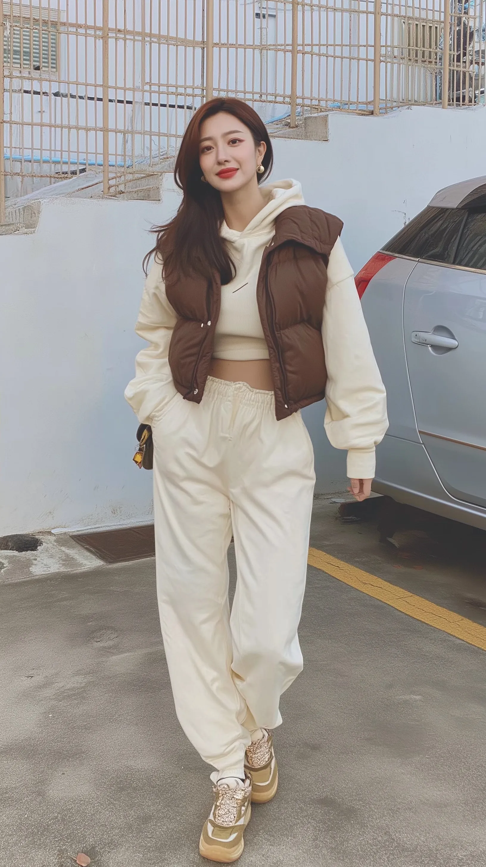 Korean woman posing in a trendy puffer vest, fleece hoodie, and tapered joggers for a casual first date outfit.