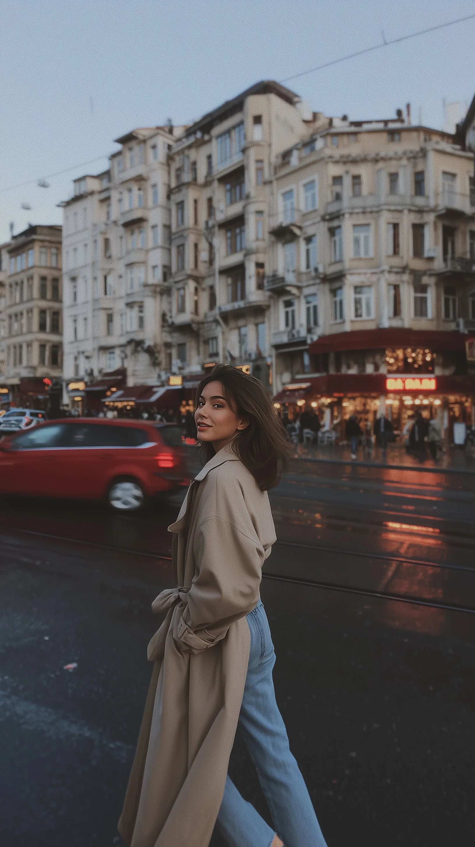 A stylish young woman in a trench coat crossing a street in Istanbul, candid fashion photography with natural light.