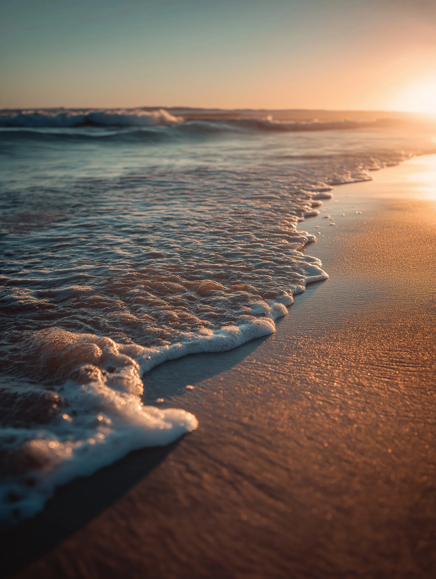 Golden hour sunset at an Australian beach with soft waves washing over golden sand in a cinematic wide shot.