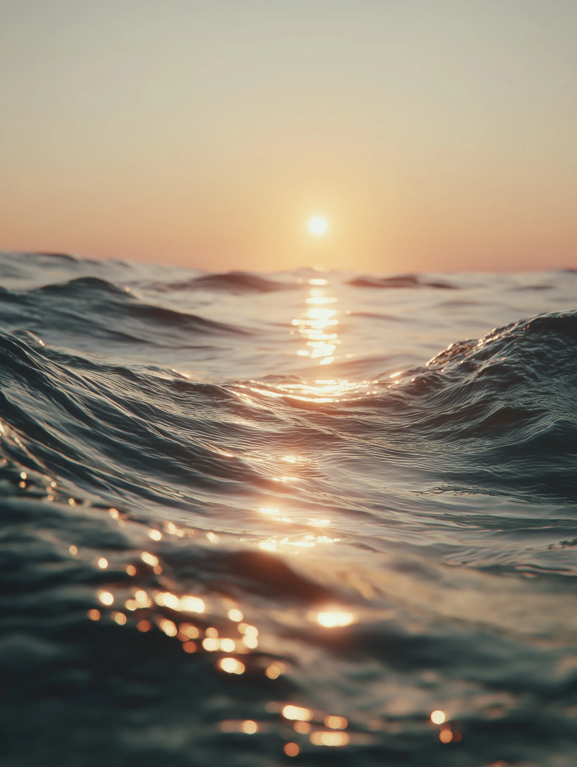 Golden hour sunlight reflecting on gentle ocean waves with a soft-focus, cinematic aesthetic and pastel tones.