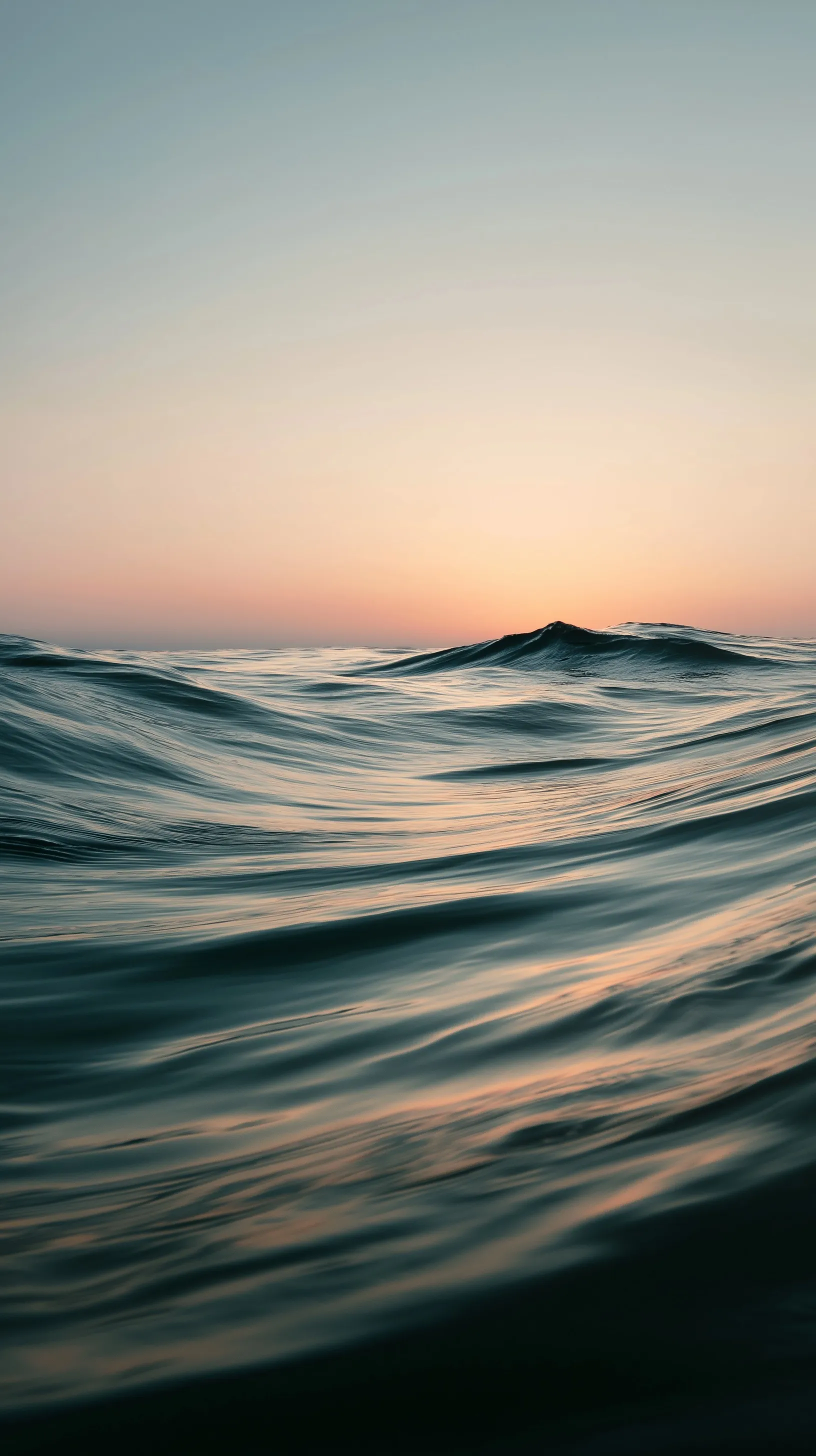 Gentle, slow-moving ocean waves during a golden hour sunrise with soft, natural light and a calm, minimal aesthetic.