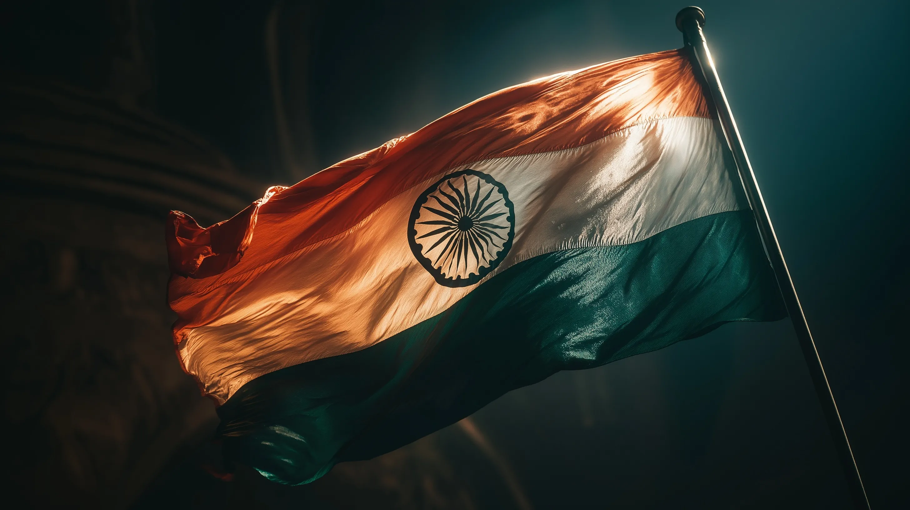 Indian tricolor flag glowing under a spotlight against a dark backdrop in a static, realistic press-style shot.