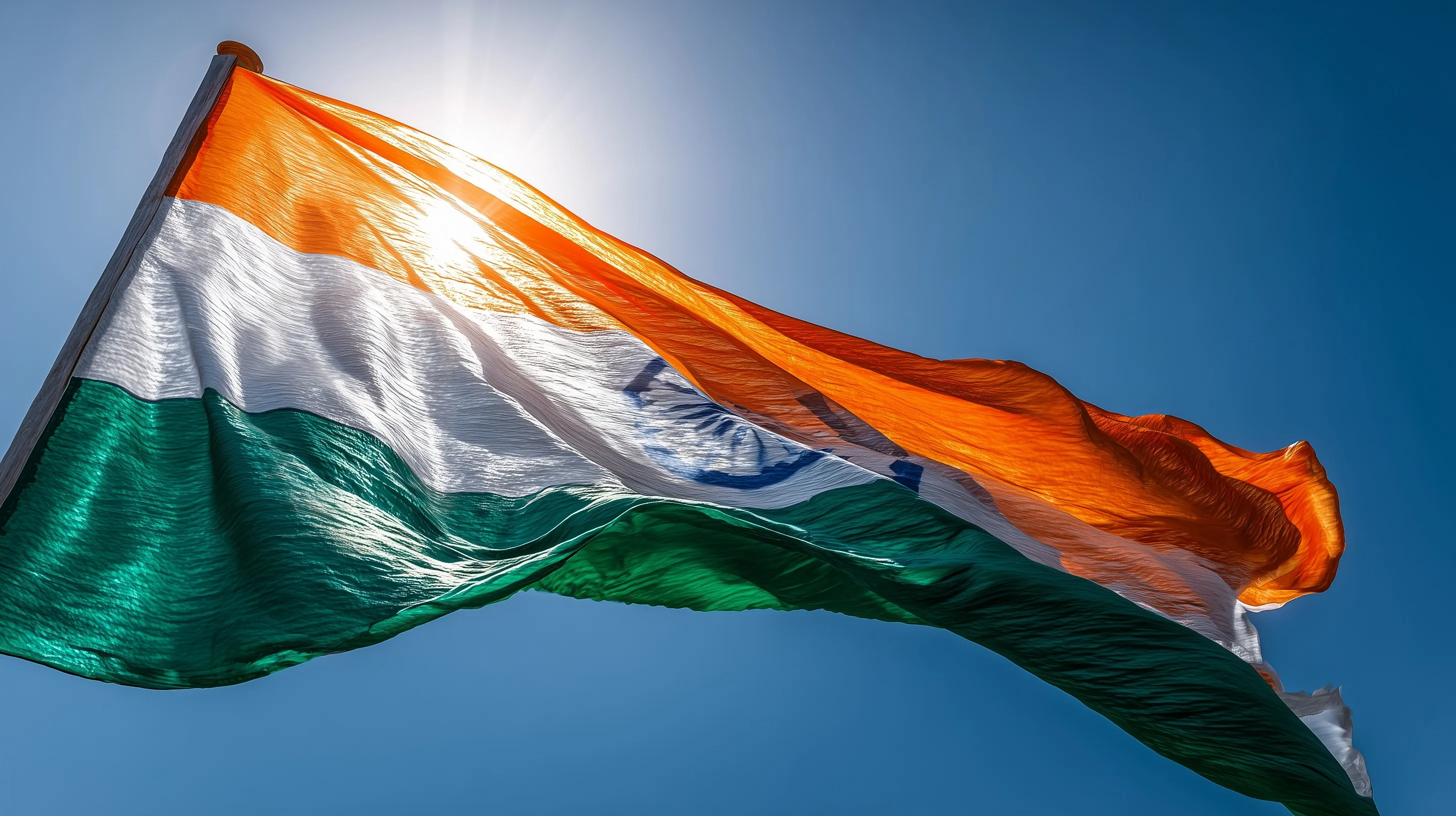 A large Indian tricolour flag waving against a clear, vivid blue sky with realistic fabric folds and sunlight.