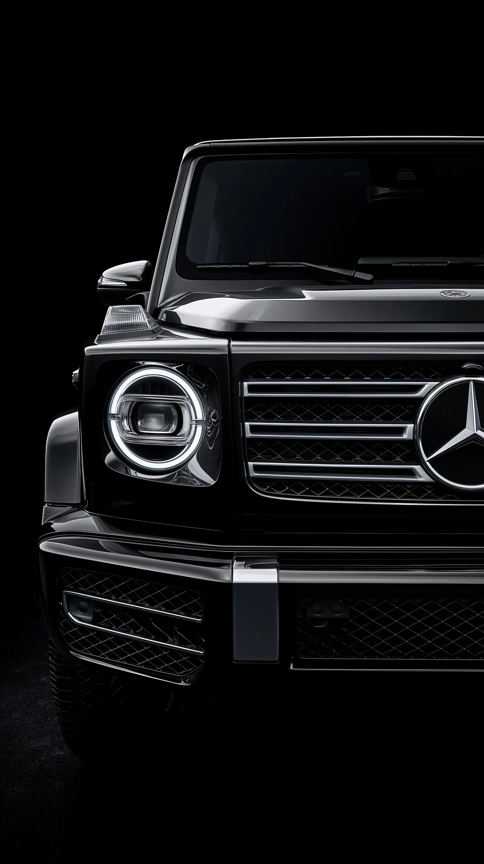 Close-up symmetrical shot of a 2025 black Mercedes G-Class front and hood with glossy chrome details.