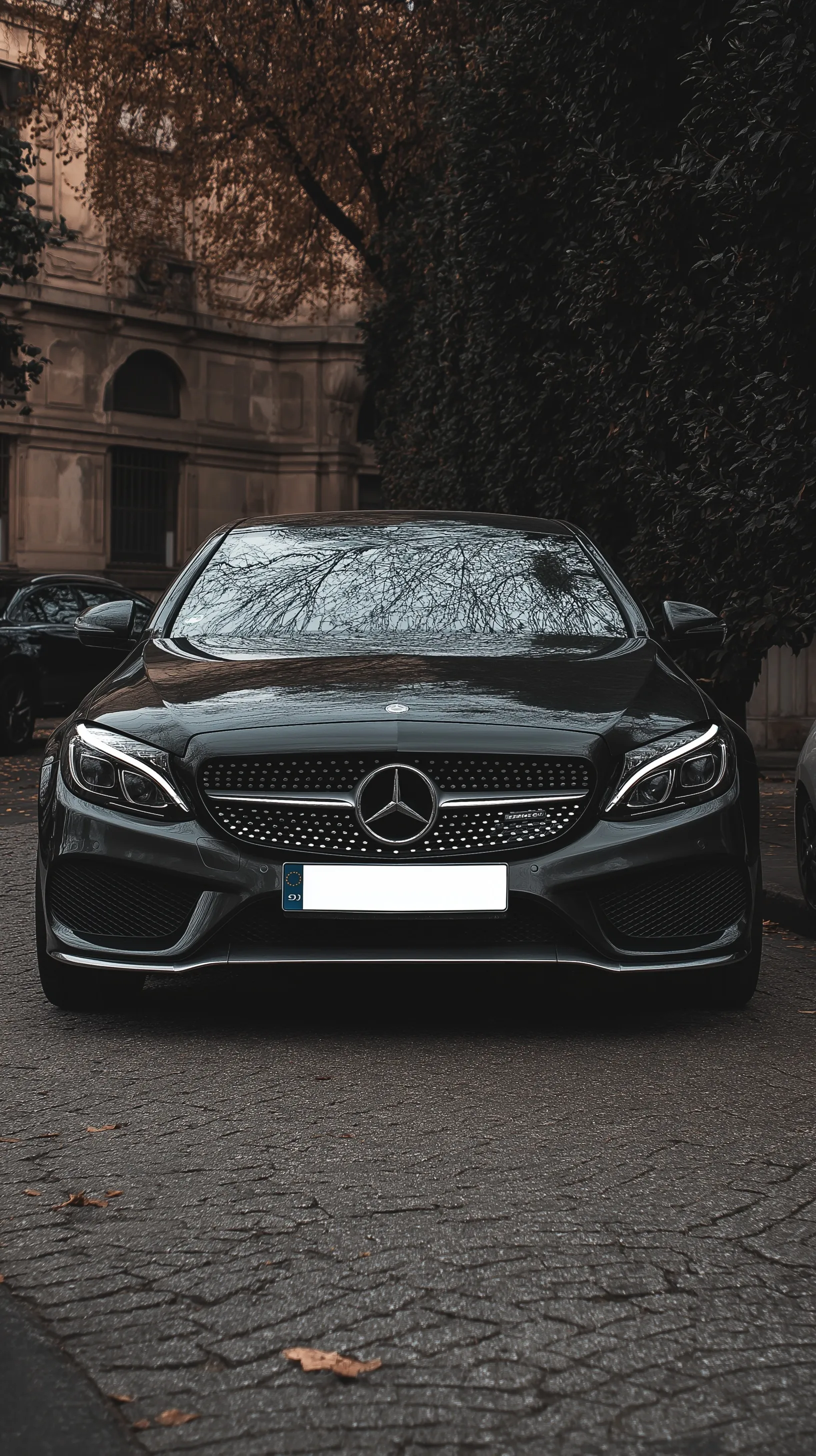Front view of a sleek black Mercedes luxury car with a blank license plate for smartphone backgrounds.