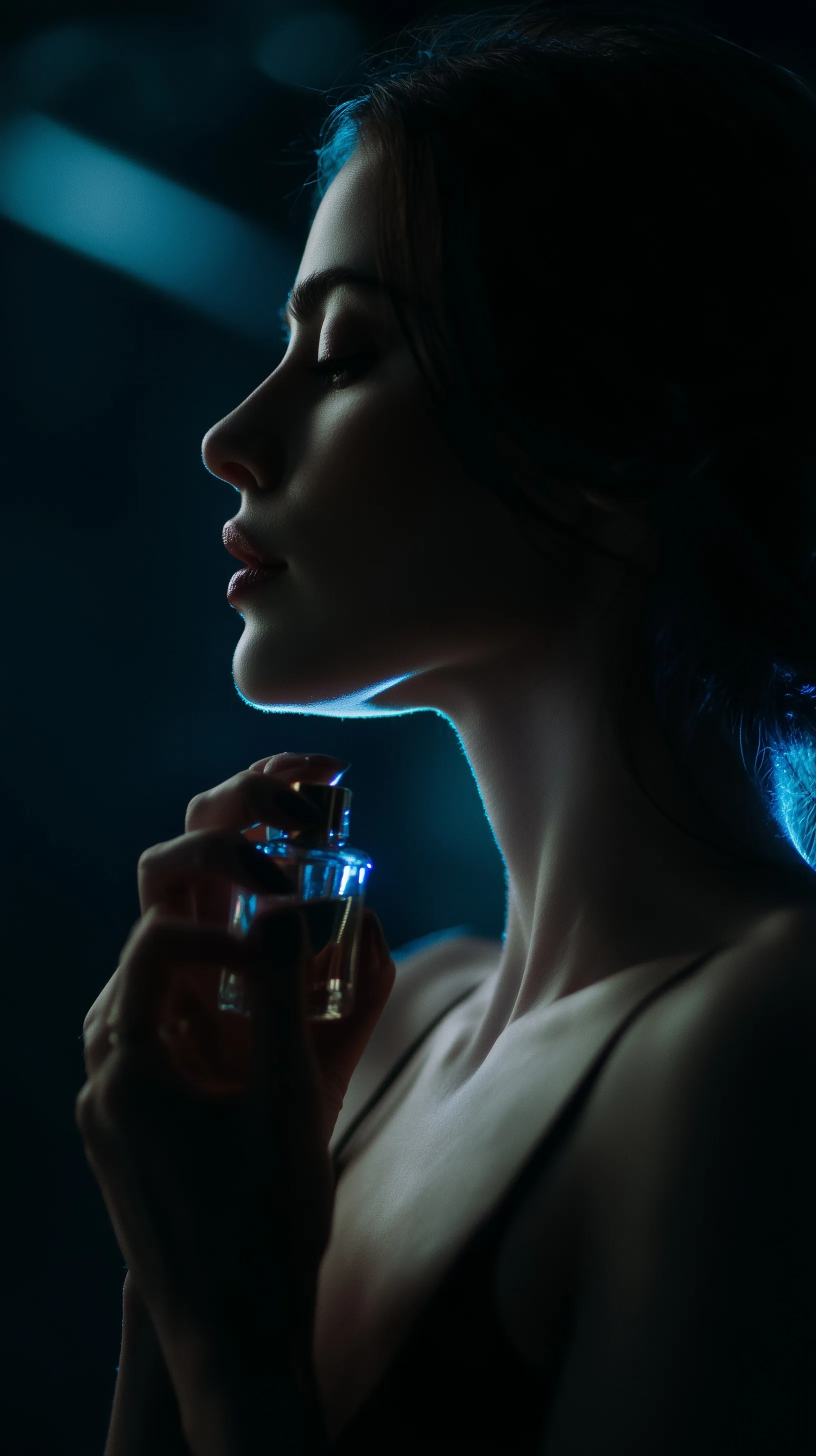 A young woman with bioluminescent skin applying perfume in a cinematic chiaroscuro lighting setup.