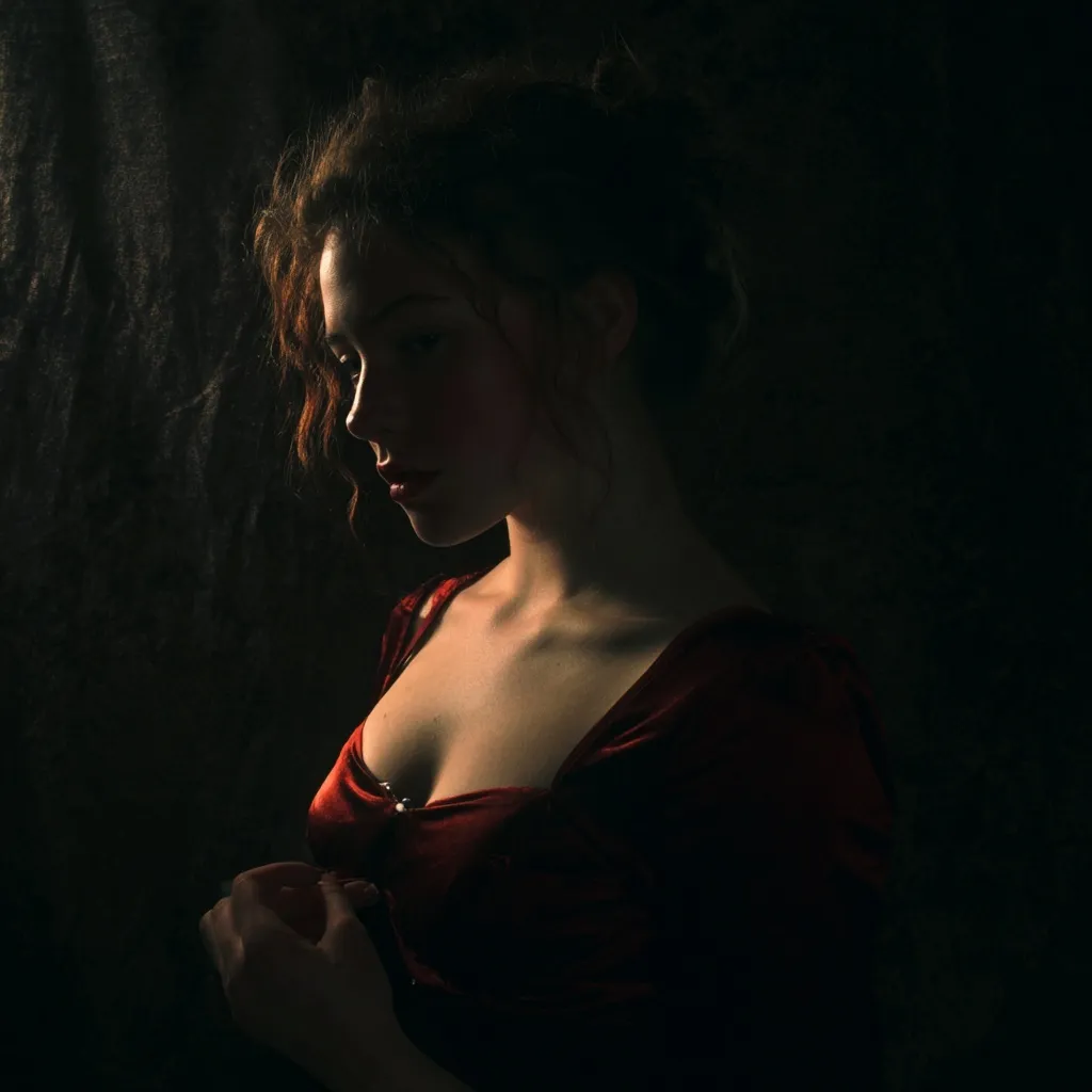 A model posing in dramatic chiaroscuro lighting with high-contrast shadows and artistic highlights.