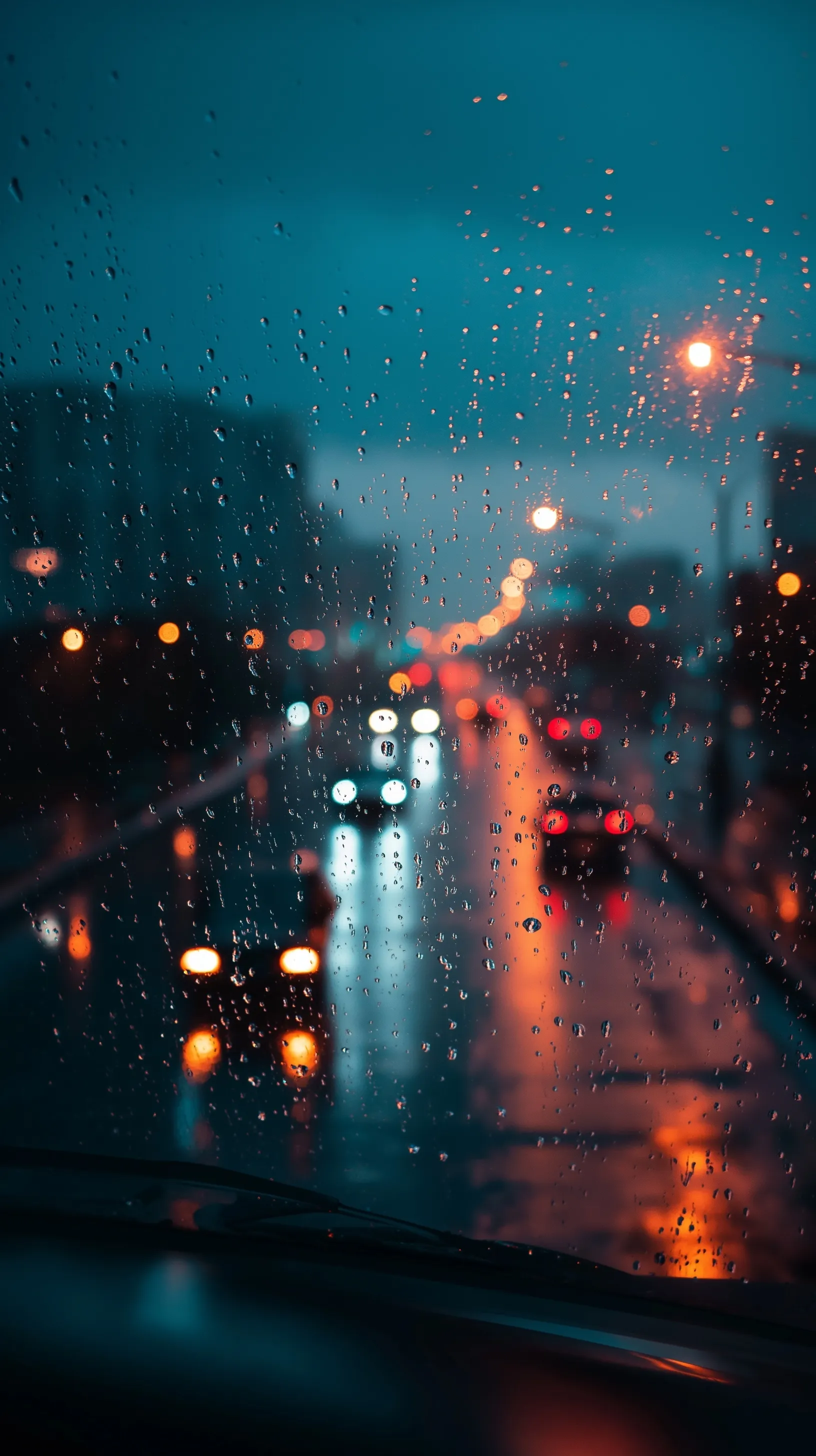 Rain droplets on a car window with blurred city lights in the background for a cinematic, moody atmosphere.
