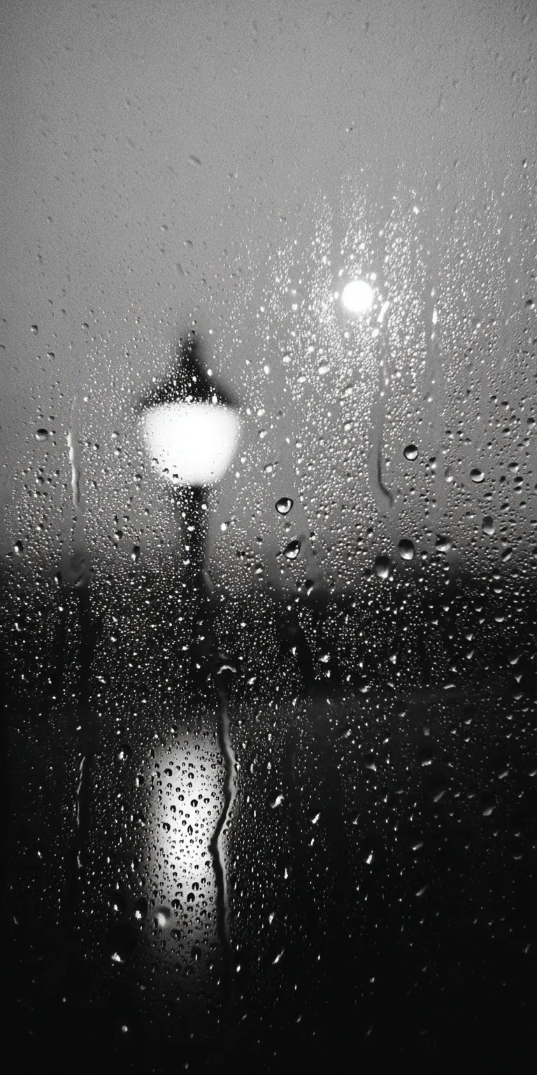Close-up of raindrops on a window pane at dusk with moody, monochromatic film grain and warm streetlight reflections.