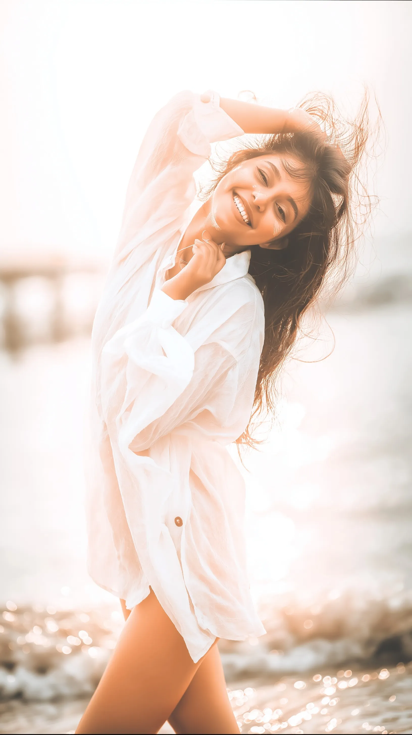 Beautiful young woman walking on a pristine beach at sunset with flowing hair and turquoise sea in the background.