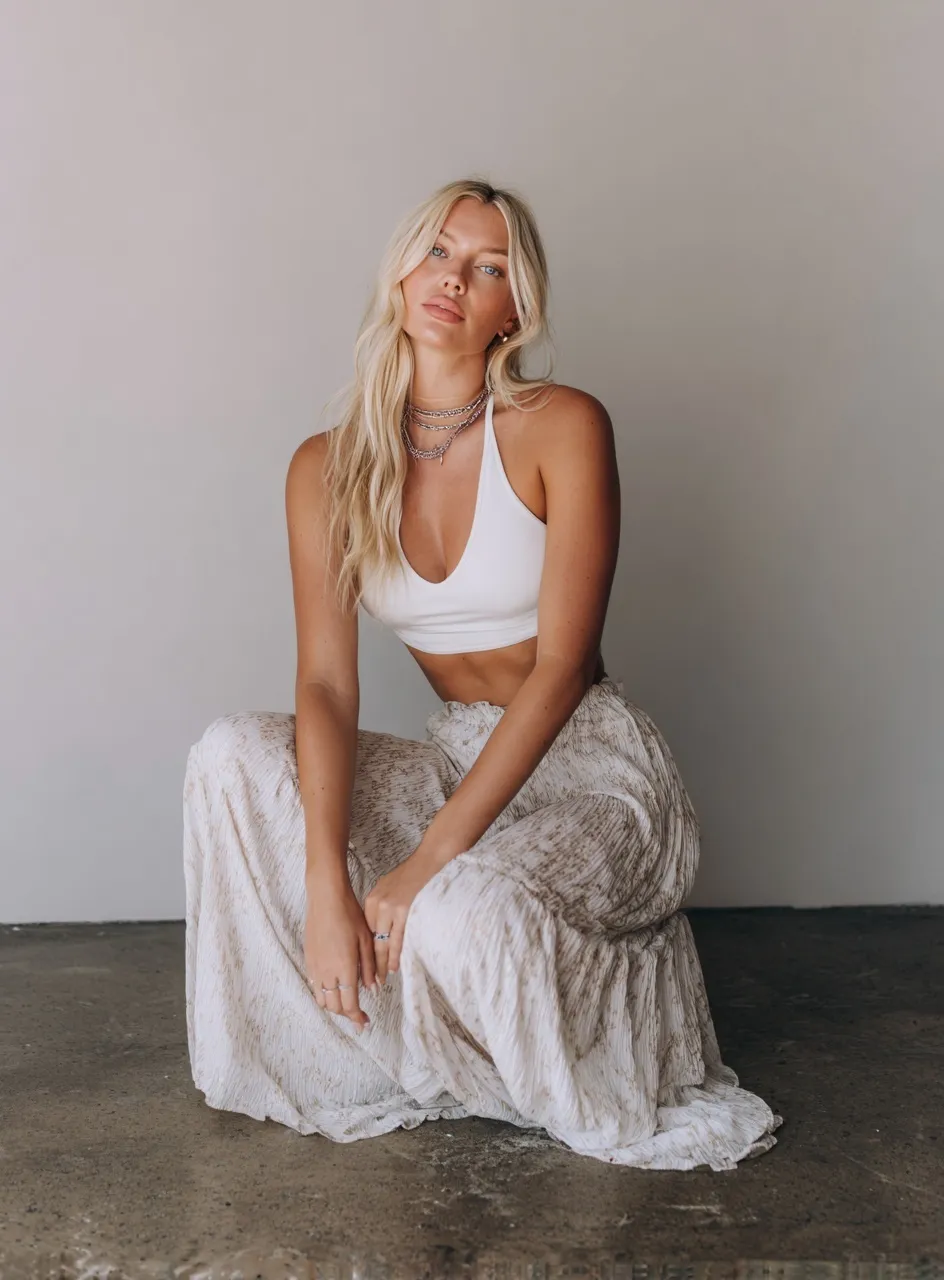 Blonde influencer posing in a white ribbed tank top and long skirt for an Instagram style fashion photo.