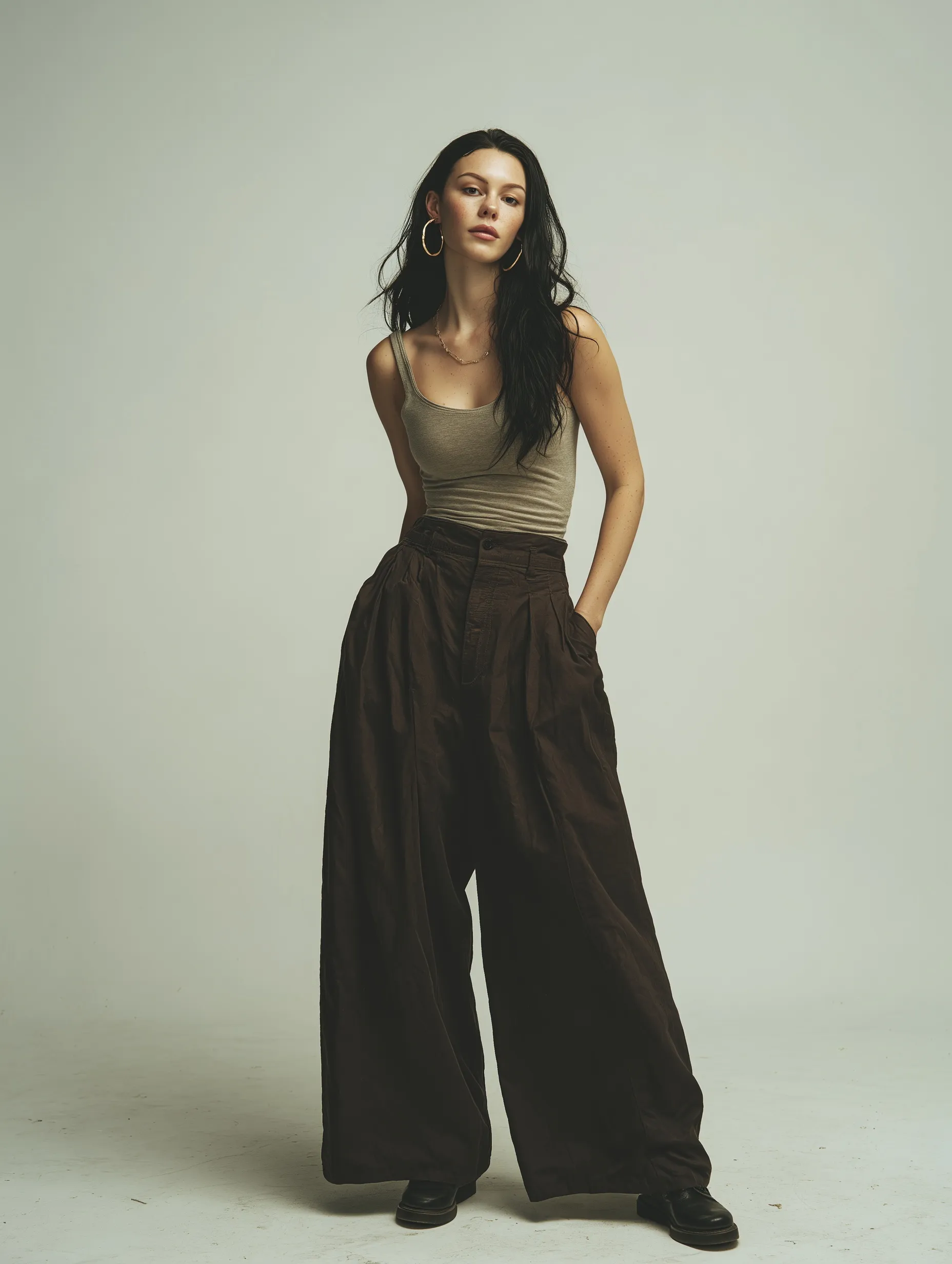 European woman in a ribbed yoga tank top and wide-leg pants posing in a professional photography studio.
