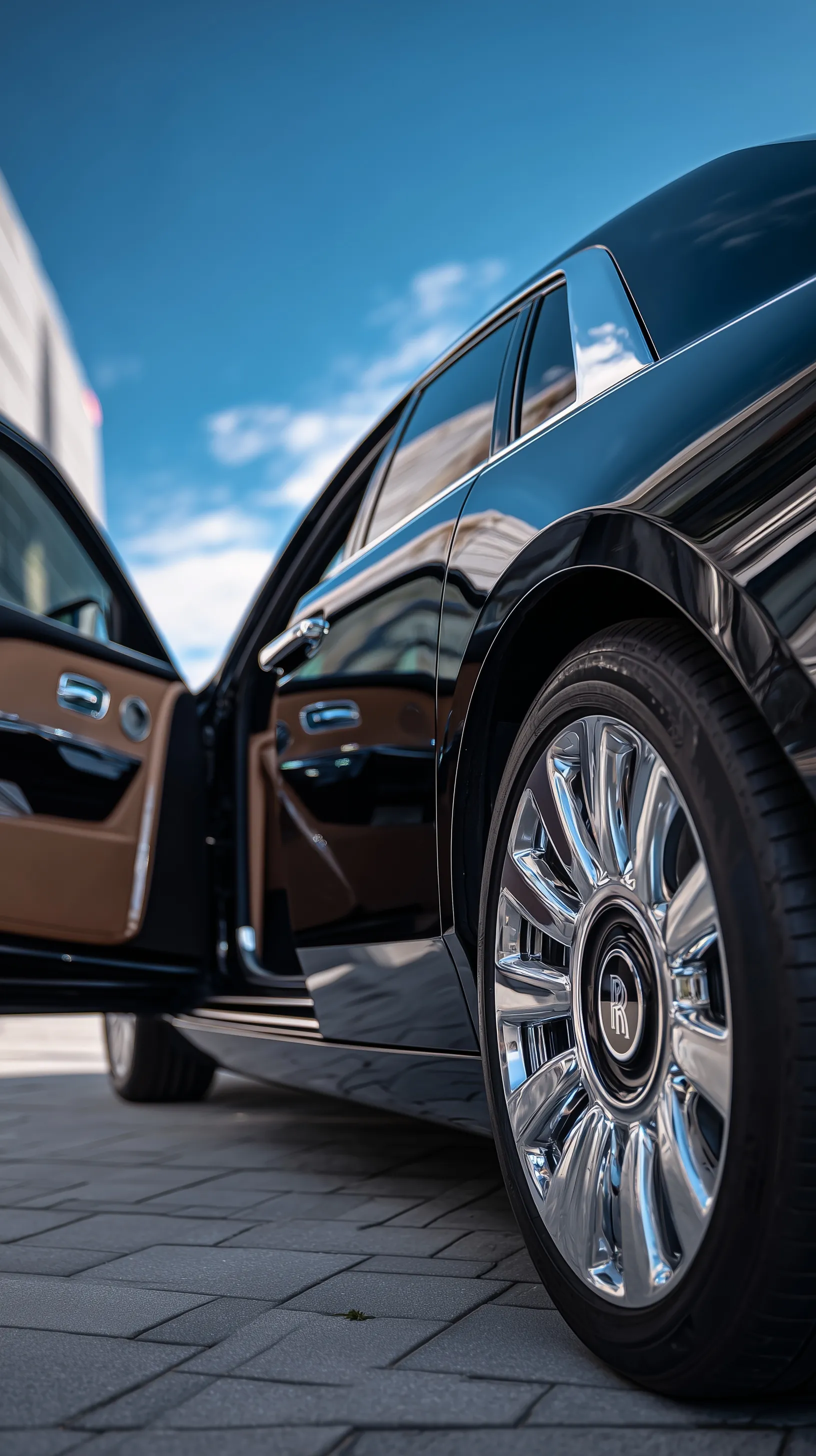 Close-up of a black Rolls Royce luxury car with door open, showcasing premium leather interior and glossy chrome.