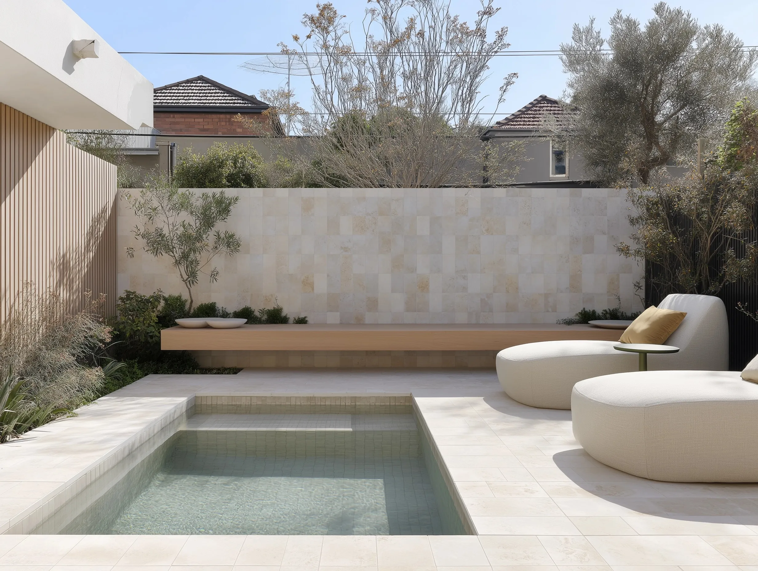 Small geometric backyard pool with sun loungers and minimalist tile patio in an Australian garden setting.