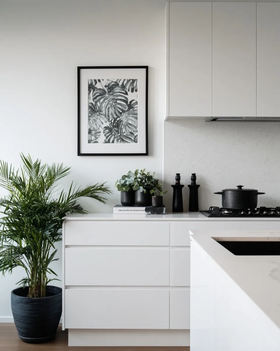 Empty framed wall art hanging on a white wall in a modern, minimalist plant-based kitchen with greenery.