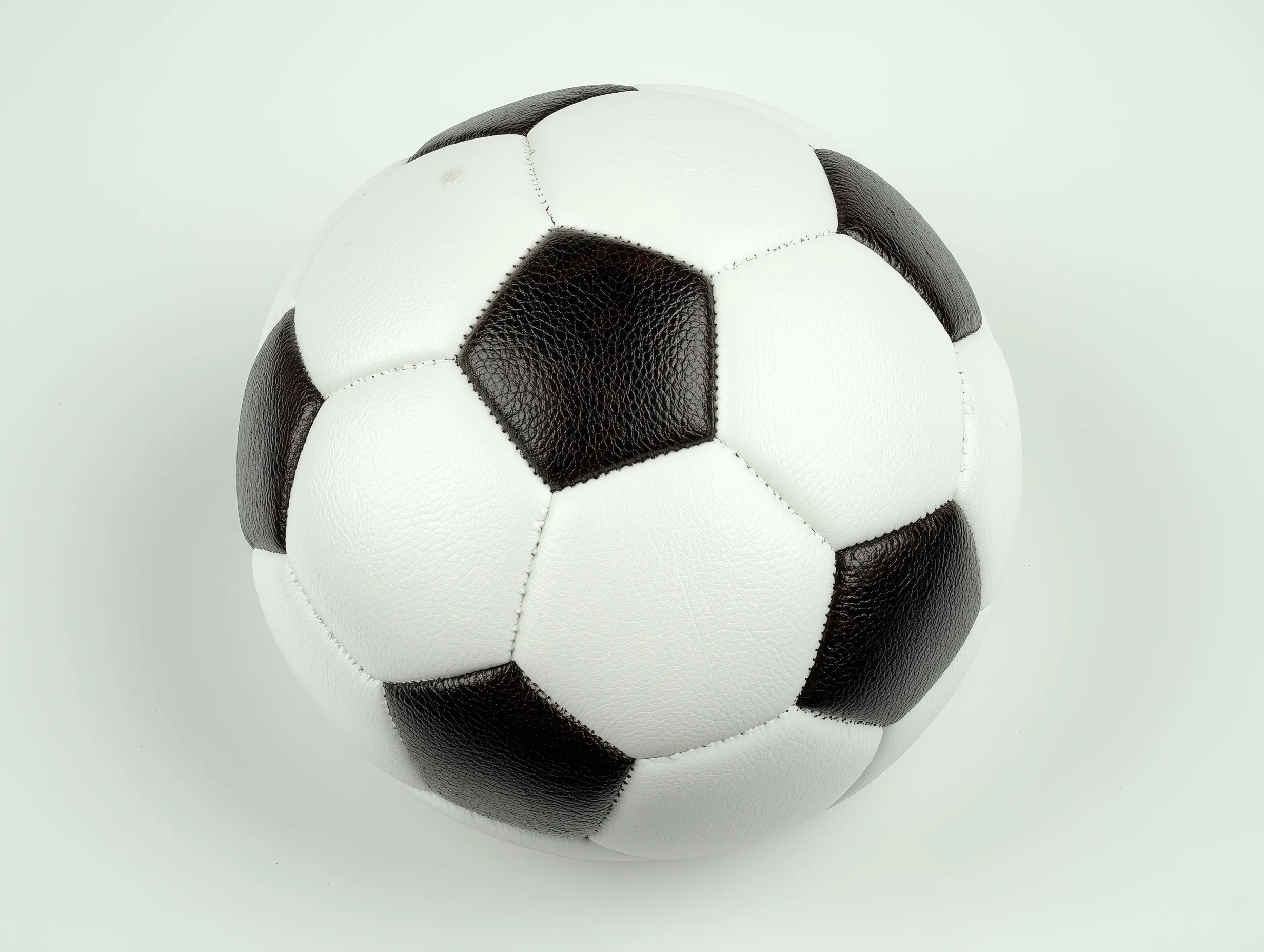 A classic black and white leather soccer ball floating in mid-air against a clean, isolated white background.