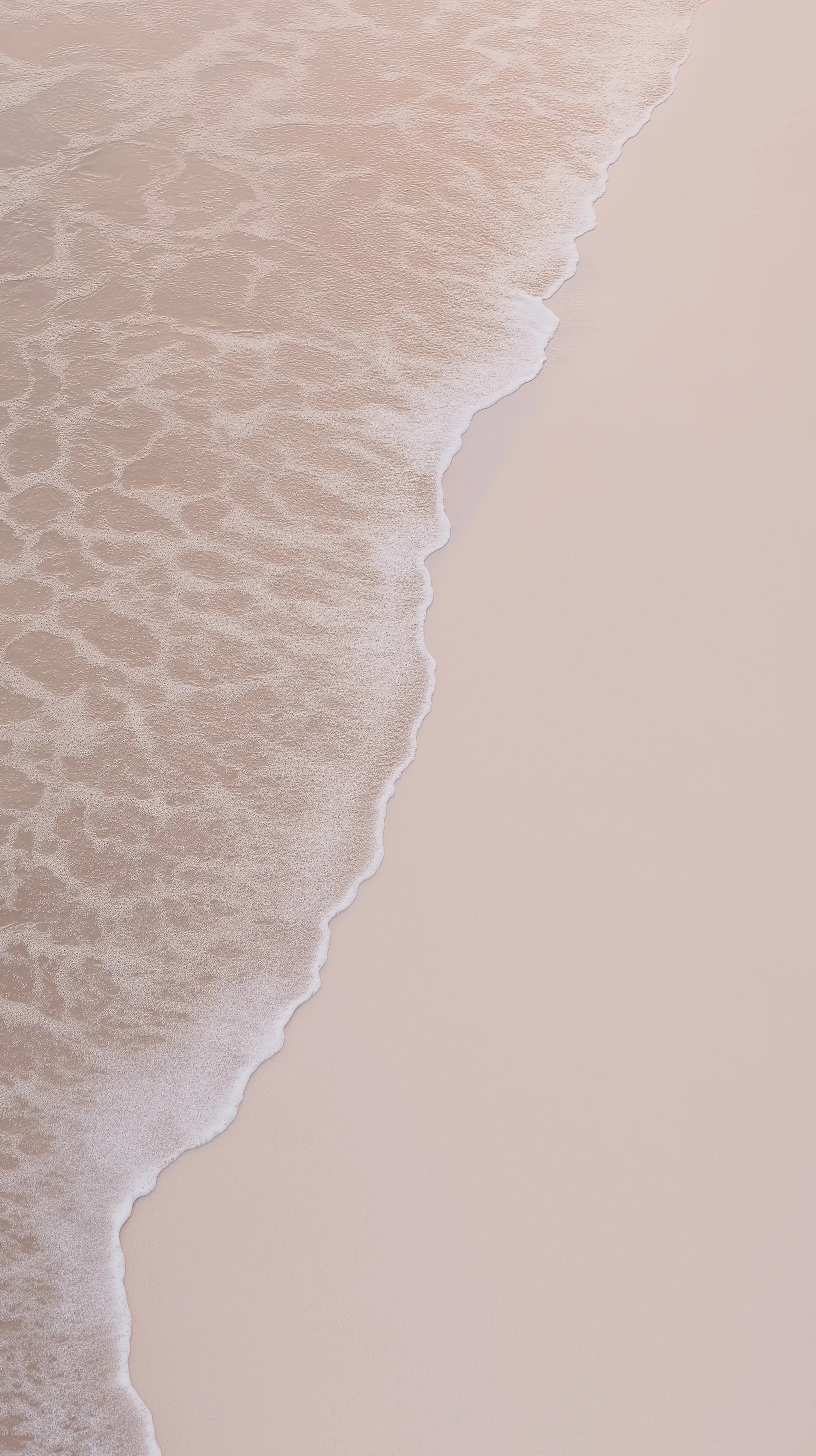 Minimalist shoreline at golden hour with soft pastel colors, gentle sea waves, and textured sand, no people.