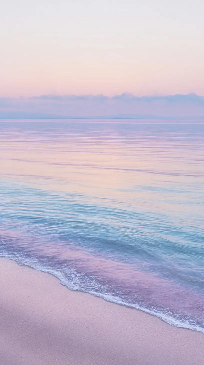 Pastel sunrise over a calm turquoise beach with gentle sea ripples and soft pink-violet sky at dawn.
