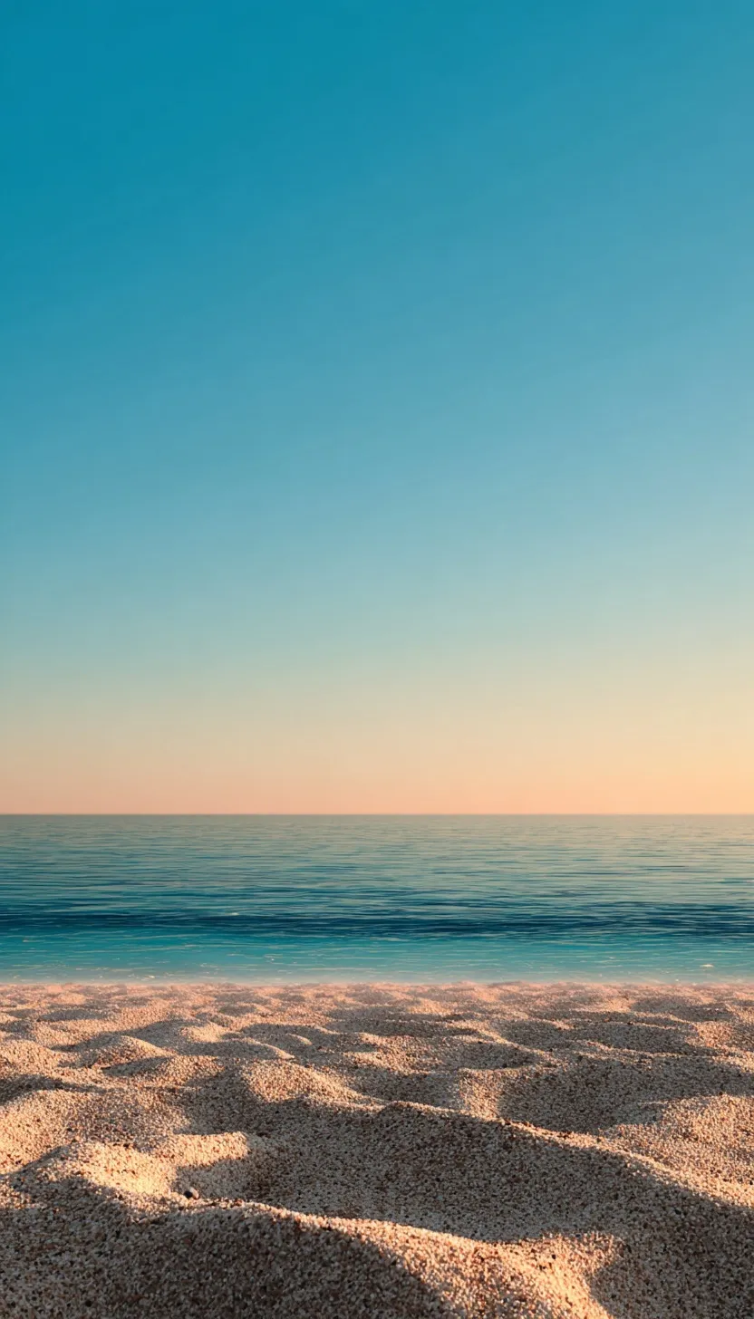 A minimal paradise beach view featuring golden sand, calm blue sea, and a clear sky at sunset.