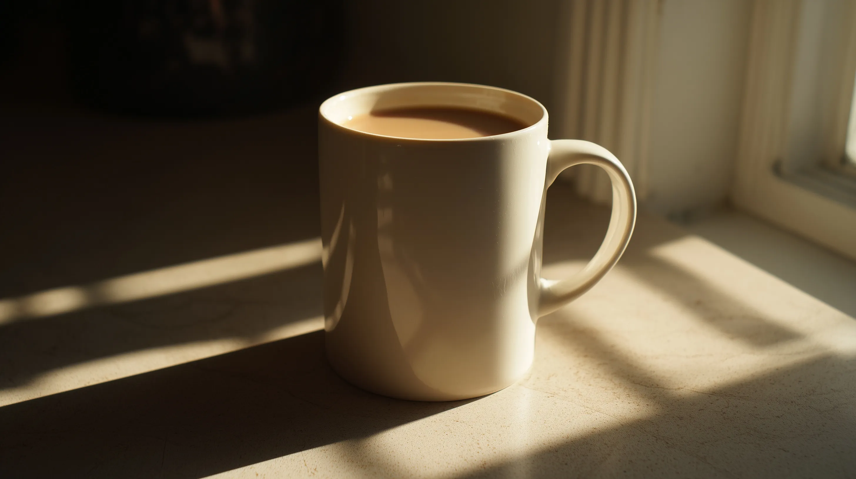 A white ceramic coffee mug filled with creamy coffee on a table, captured with natural light and chiaroscuro.