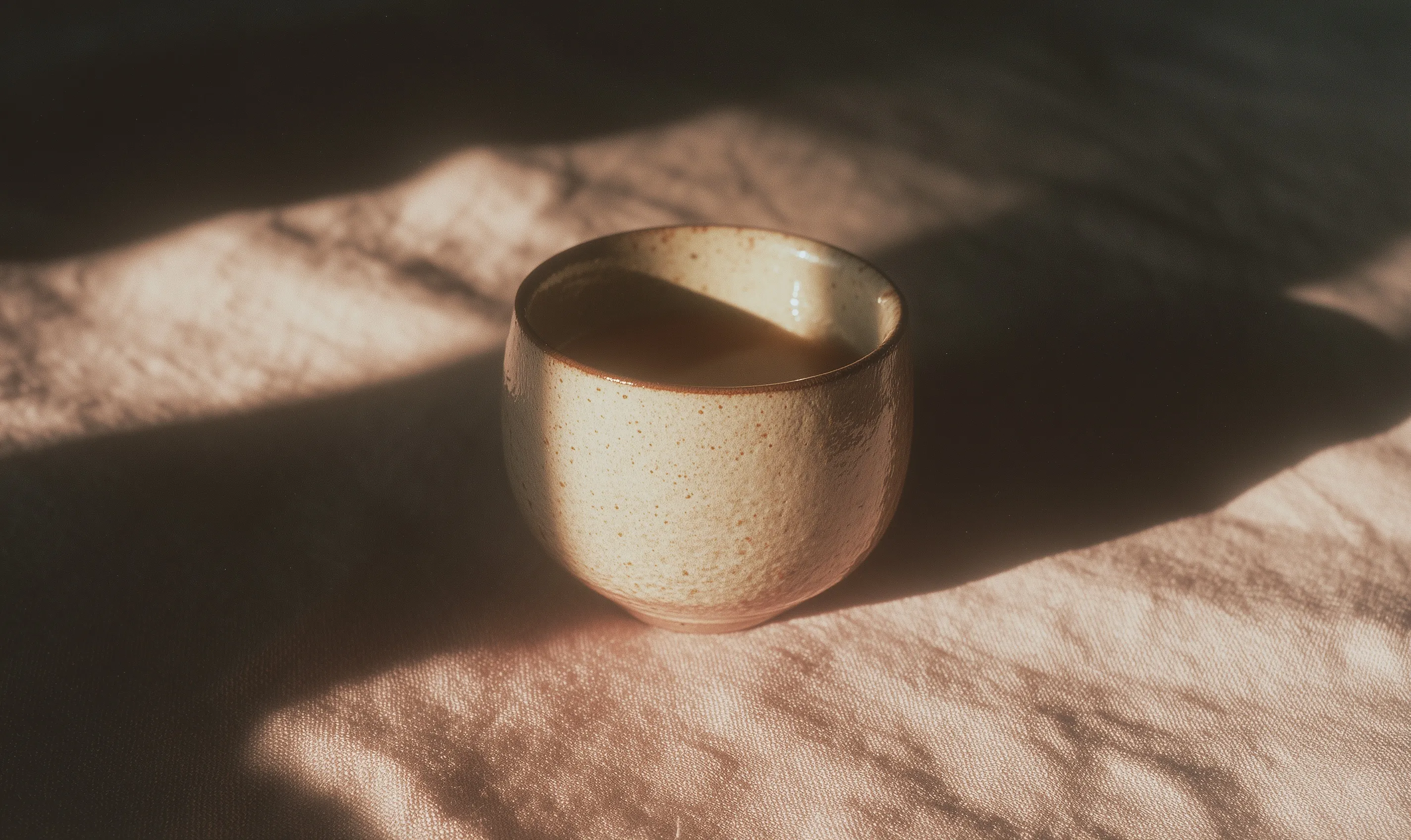 Minimalist ceramic coffee mug on linen, shot in analog film style with hard flash and warm, creamy tones.