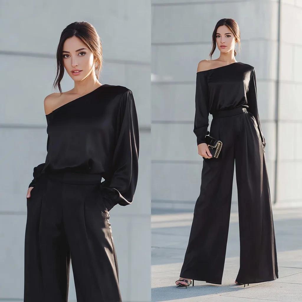 A 35-year-old European woman in an elegant satin one-shoulder blouse and flowing wide-leg pants on a city street.