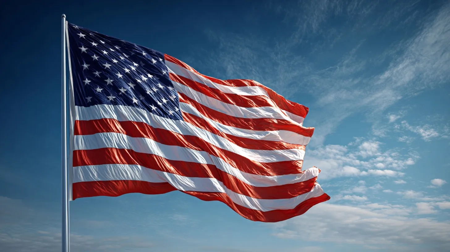 A large American flag waving proudly against a clear blue sky, capturing rich fabric details and patriotic motion.