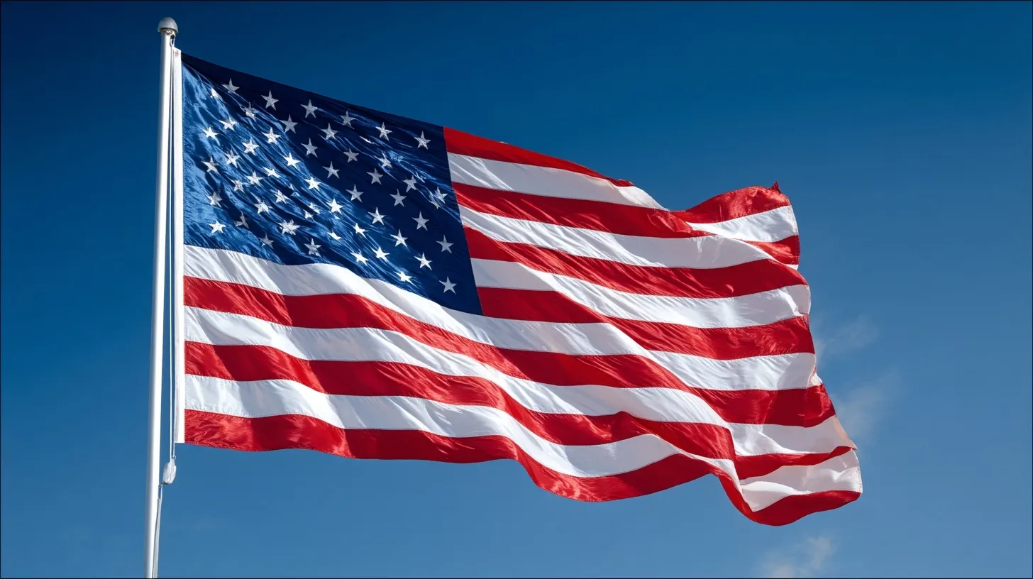 Close-up of an American flag waving against a clear blue sky on a bright, sunny day.
