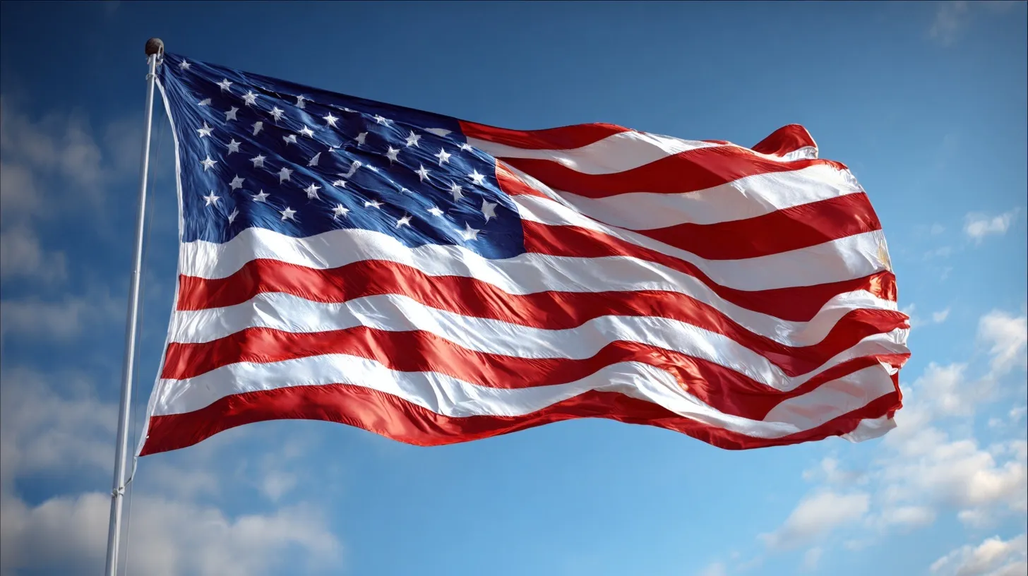 A large American flag waving proudly in the wind against a clear blue sky background.