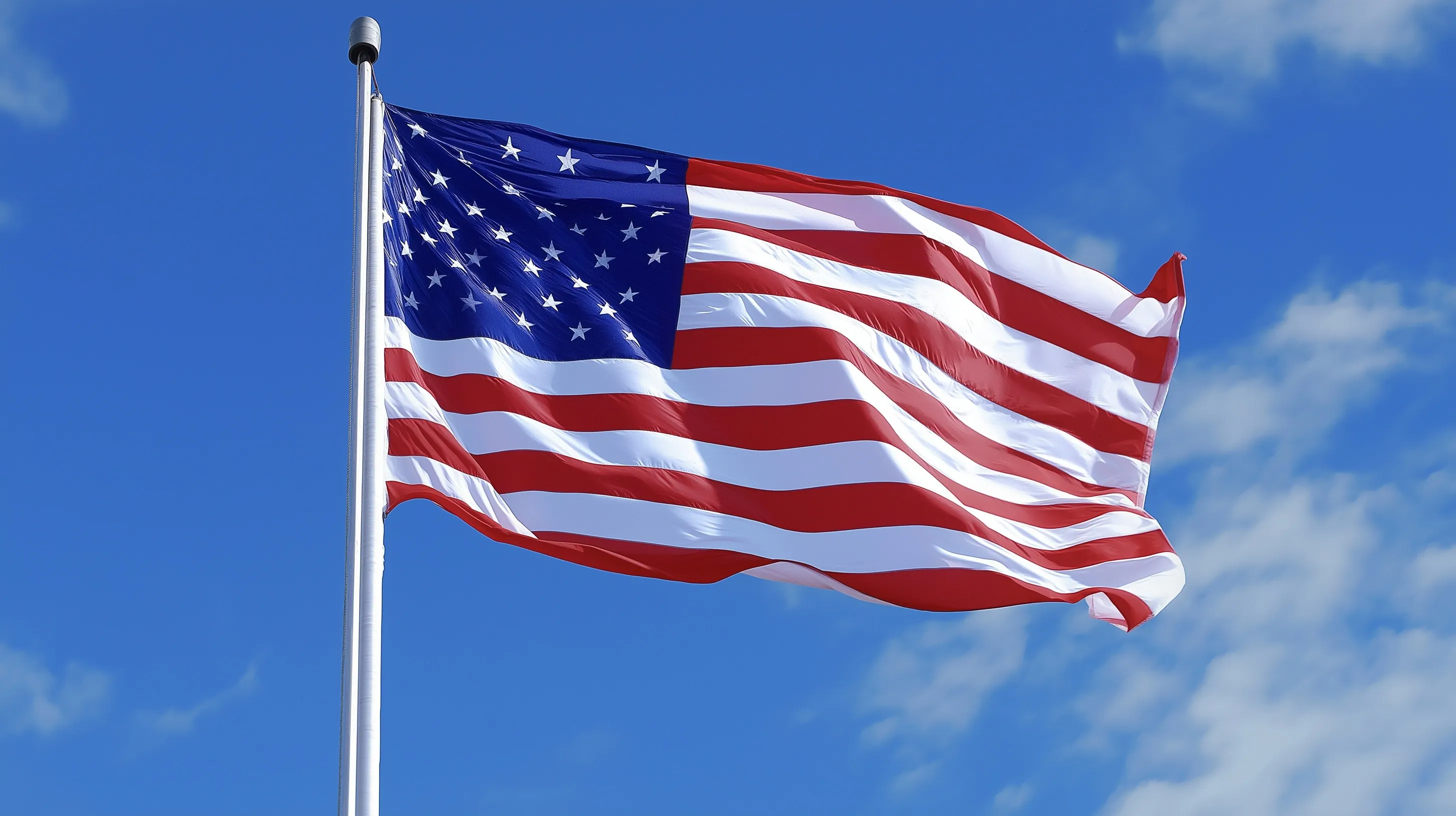 A vibrant USA flag waving against a clear blue sky on a bright sunny day.