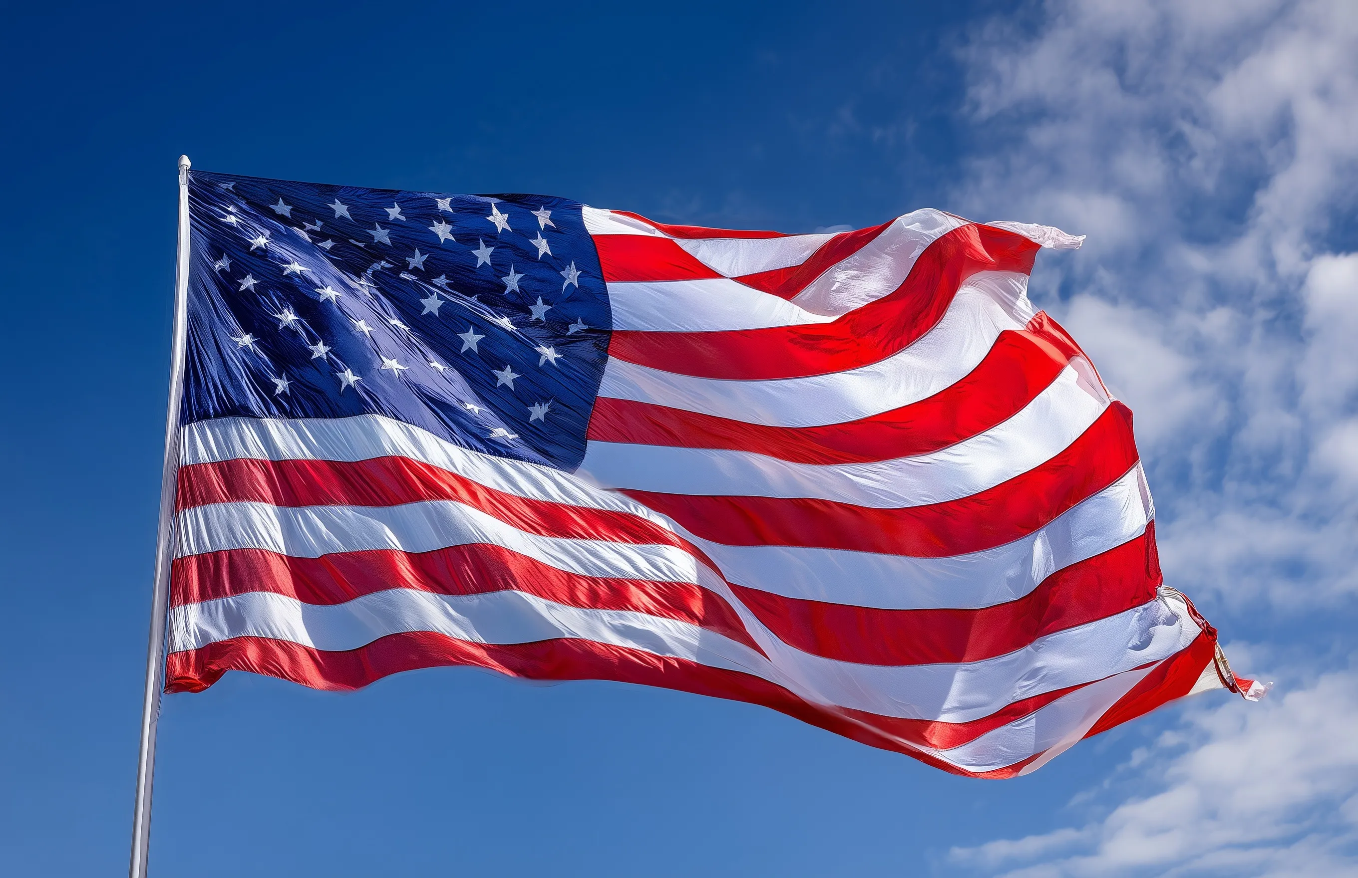 American flag waving in the wind against a clear blue sky, high-resolution stock photography.