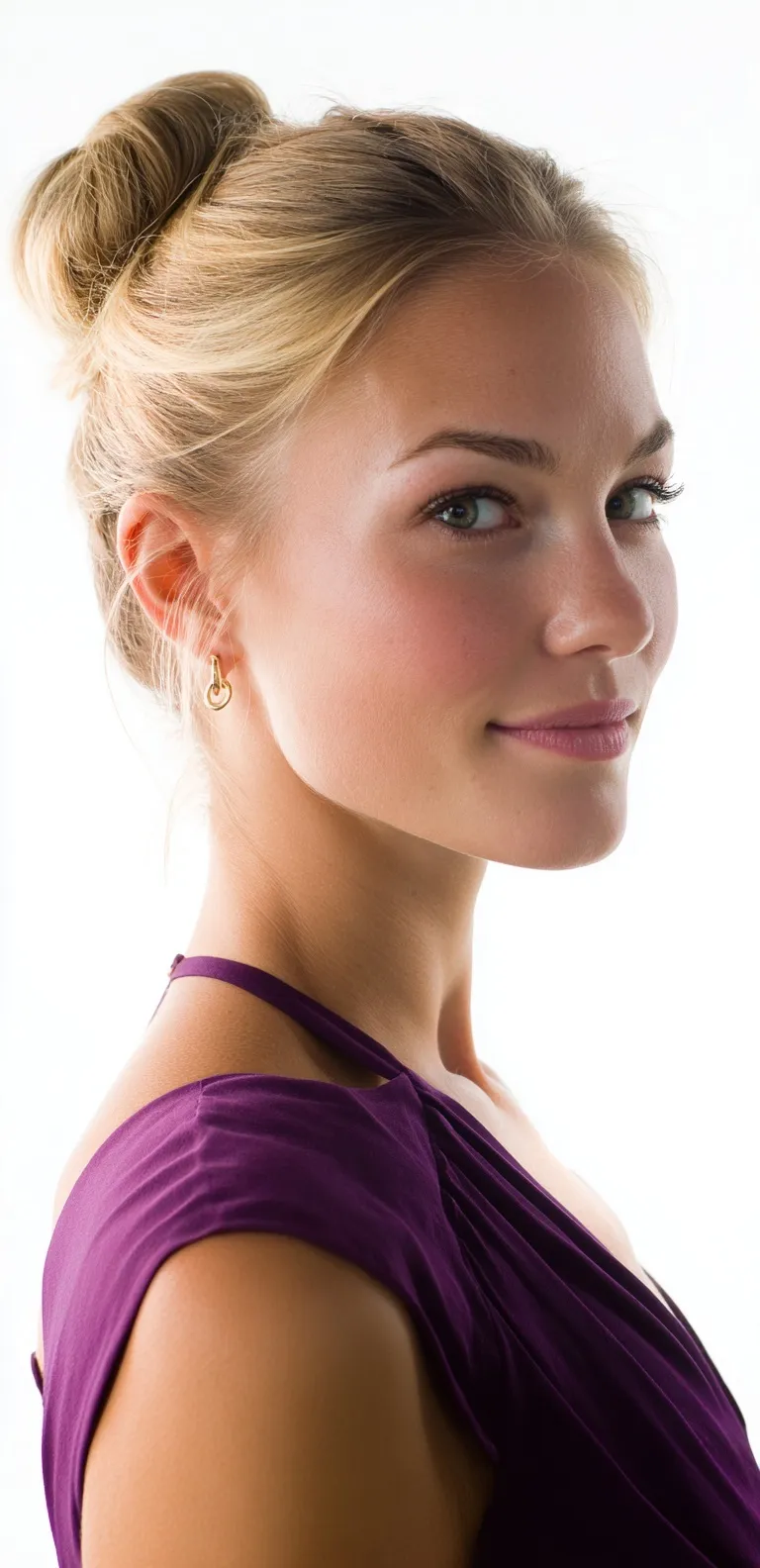 Blonde woman in a purple dress with an elegant, neat bun hairstyle posing for a professional wedding guest portrait.